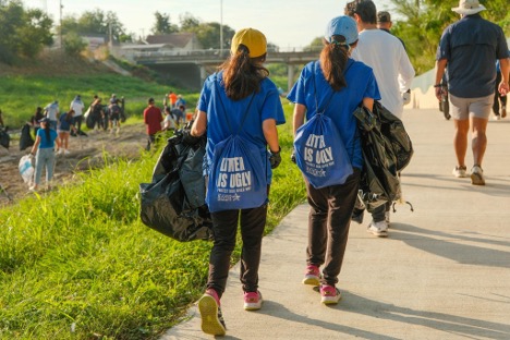 A group of volunteers walks together on a park trail during a cleanup.