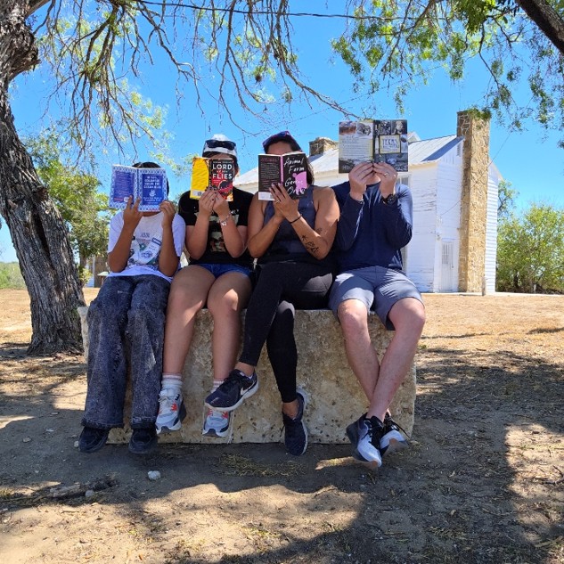 A group of people sit together with their noses in books