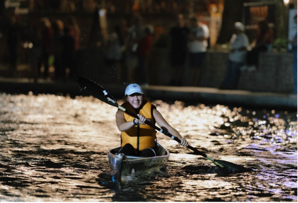 A woman kayaks at night during the Downtown Race the River Event.